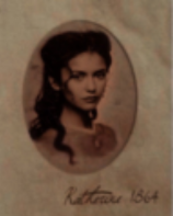 La photographie est en noir et blanc mais sur un papier très ancien, elle ressort donc dans les tons plutôt sepia. Elle représente une femme blanche née au 19ème siècle, nommée Katherine. Elle a des cheveux très foncés et ondulés semi attachés en arrière, des sourcils et un nez assez fins, ses yeux sont sombres et perçants. Elle nous regarde avec un petit sourire narquois sur les lèvres, pourtant l’émotion de son visage est neutre. Elle se tient de 3/4, elle est vêtue d’une robe avec des épaulettes et un collier de grosses perles blanches accompagné d’un pendentif en pierres précieuses qui orne son cou découvert.