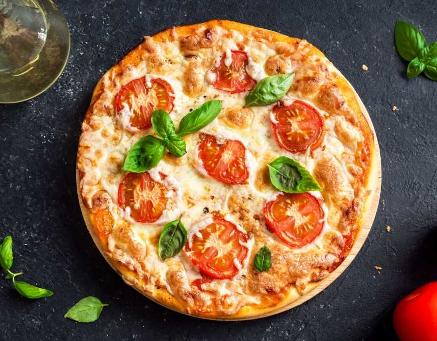 une pizza recouvert de fromage de tomate et de basilic
